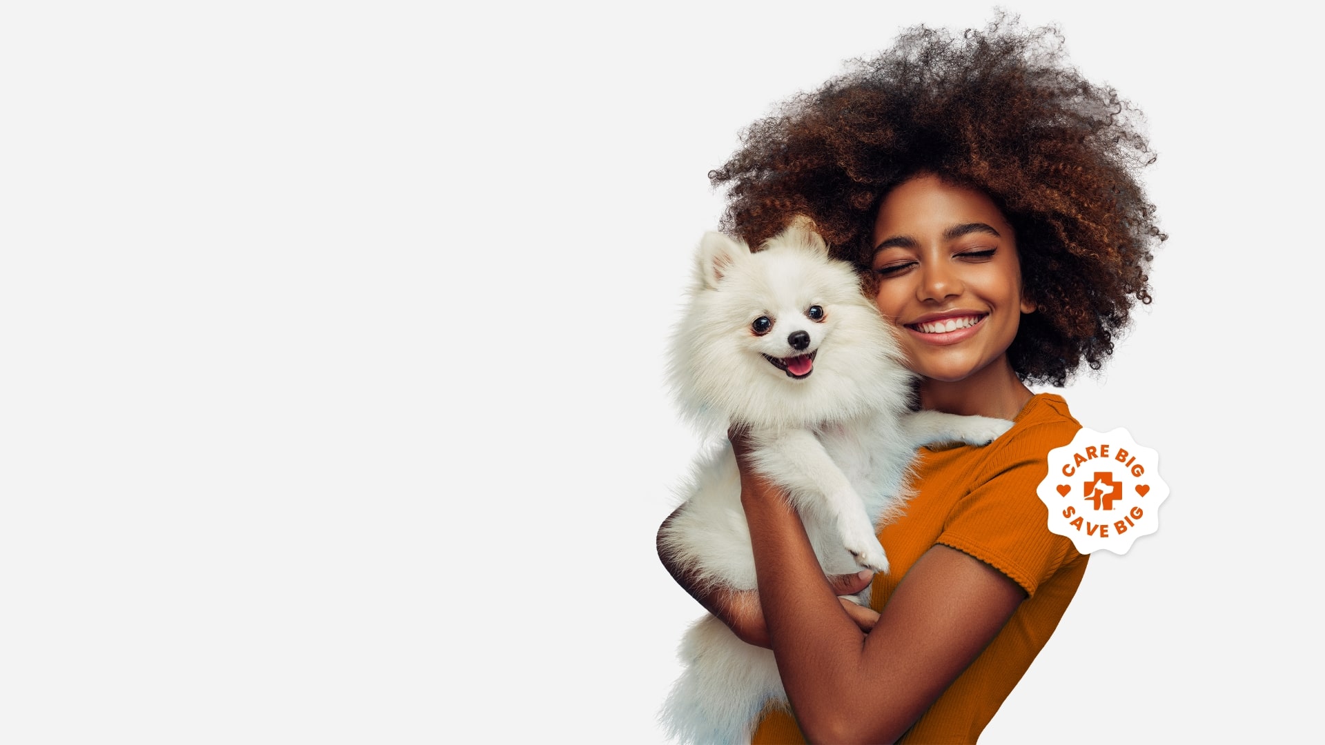A woman in an orange shirt holding a small dog