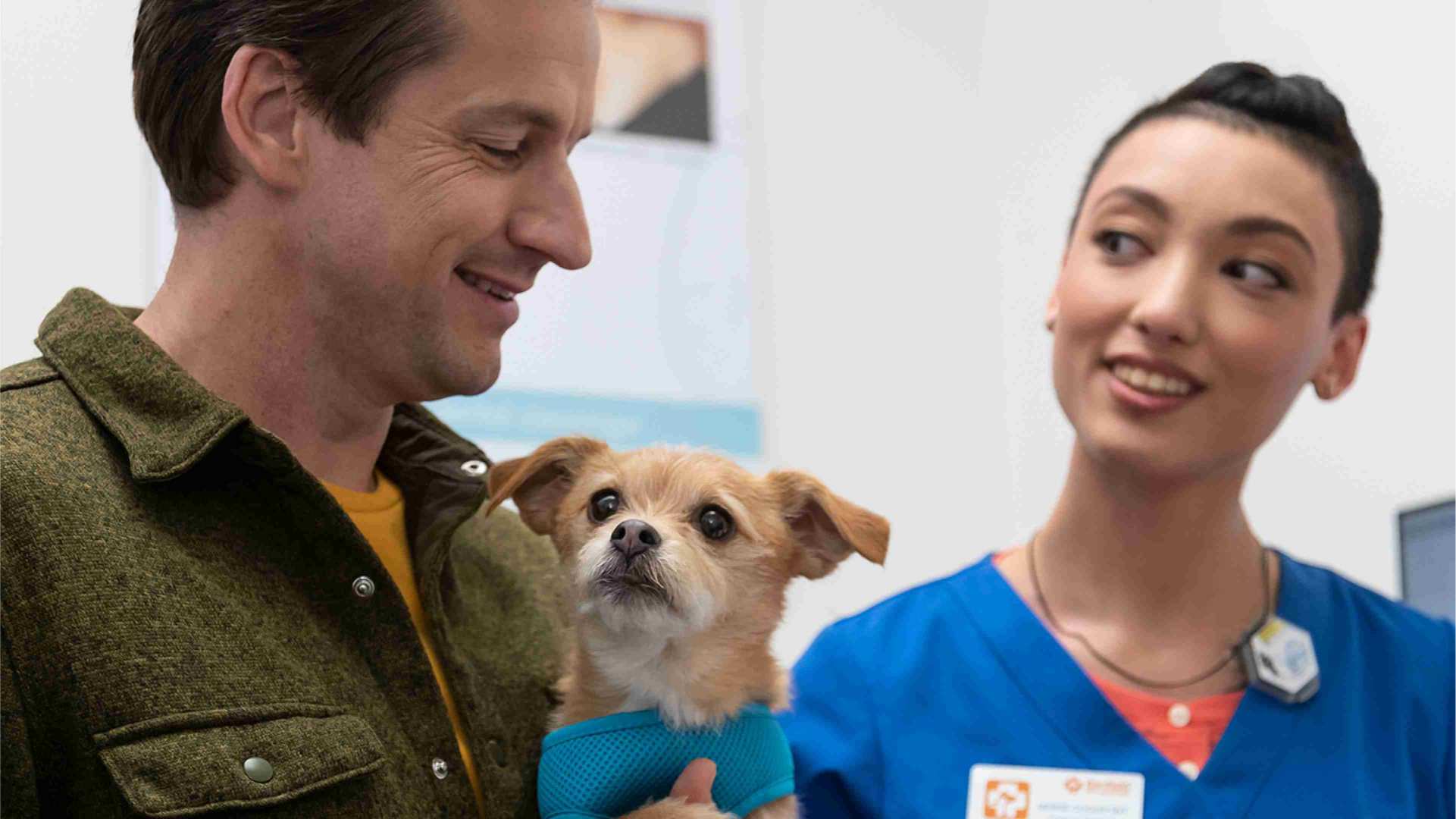 A happy man holding his puppy and interacting with a young female veterinarian at the Banfield Pet Hospital
