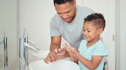 A man helping a small child wash their hands