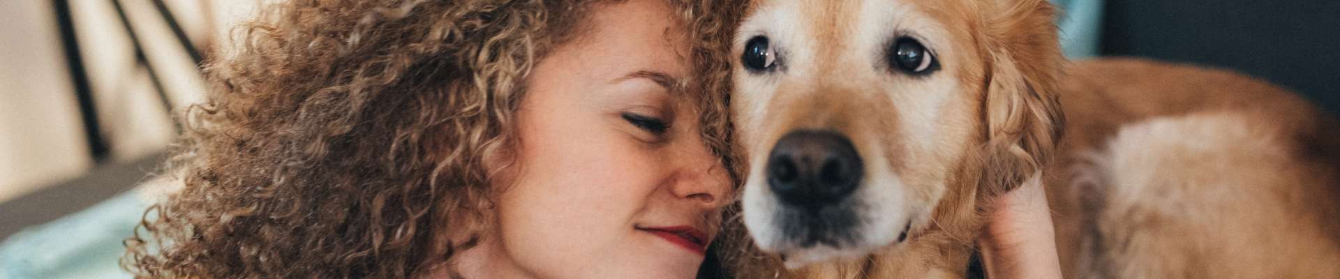 A woman nuzzling her senior golden retriever.