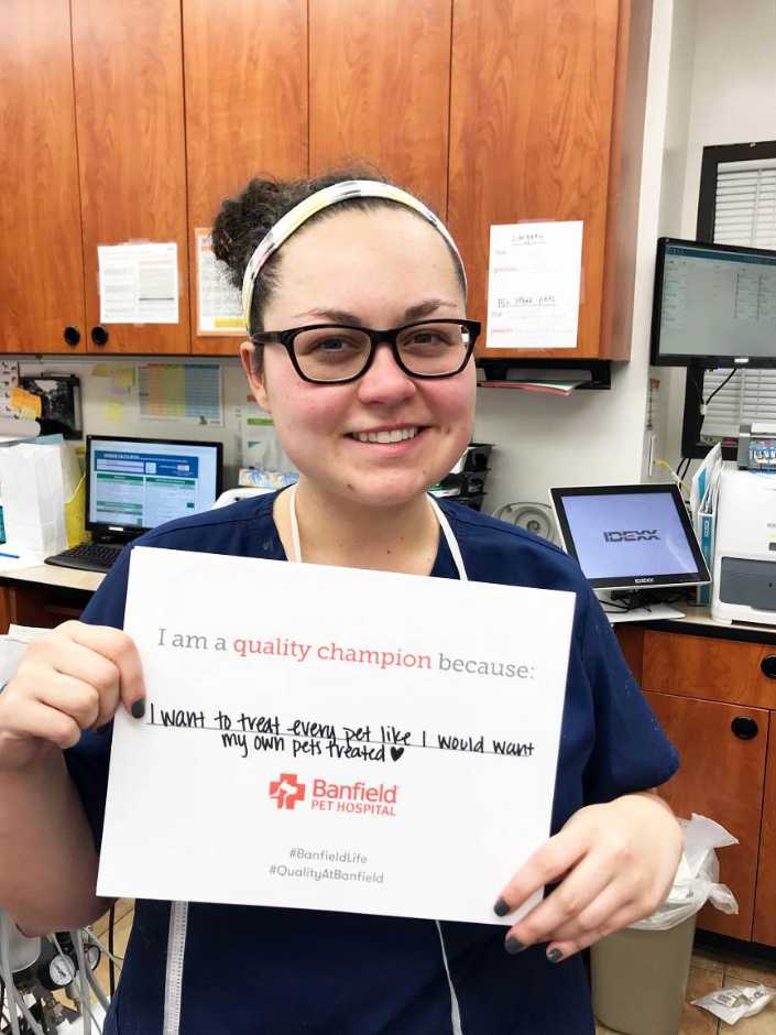 A young female associate holding a placard at the Banfield Pet Hospital